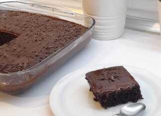 Κομμάτι σοκολατόπιτας με γυαλιστερό γλάσο κουβερτούρας να τρέχει στις πλευρές και ξύσμα πορτοκαλιού στην κορυφή