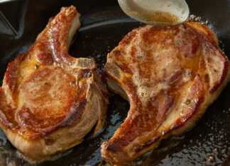 Μια καλοψημένη χοιρινή μπριζόλα με κόκαλο στο τηγάνι με χρυσαφένια κρούστα και φρεσκοτριμμένο πιπέρι