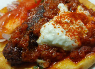 Πιάτο με ζουμερά κεμπάπ πάνω σε κομμένες πίτες περιχυμένα με κόκκινη σάλτσα και μια μεγάλη δόση γιαουρτιού