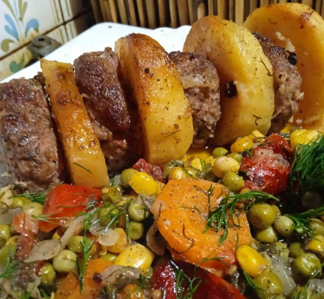 Τα ψημένα **Μπιφτέκια με Αρακά** και πατάτες στο φούρνο, σερβιρισμένα