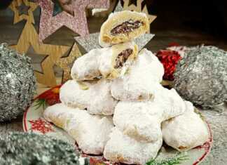 Κουραμπιέδες σε σχήμα μισοφέγγαρου, καλυμμένοι με άχνη ζάχαρη, κομμένοι στη μέση ώστε να φαίνεται η ρευστή γέμιση πραλίνας και τα κομμάτια αμυγδάλου