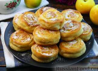 Χρυσαφένιες μηλοτηγανίτες σε σχήμα μικρού ρολού πασπαλισμένες με ζάχαρη άχνη και γεμισμένες με ψιλοκομμένα μήλα