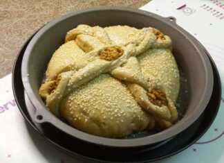 Χειροποίητο Χριστόψωμο στολισμένο με σταυρό από κοτσίδες σουσάμι και ολόκληρα καρύδια σε γιορτινό φόντο