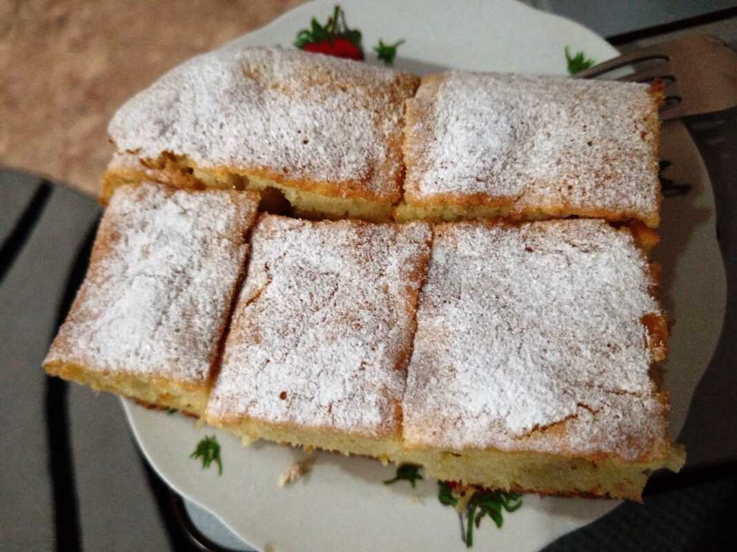 Σπιτικό κέικ γάλακτος πασπαλισμένο με άχνη ζάχαρη σε μια λαδόκολλα.
