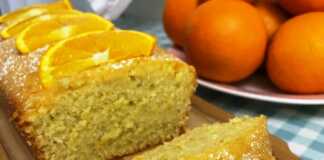 Ένα κομμάτι σιροπιαστού κέικ πορτοκαλιού πασπαλισμένο με ζάχαρη άχνη.