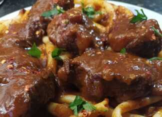 Ένα πιάτο λαχταριστής κερκυραϊκής παστιτσάδας με κομμάτια μοσχαριού και πλούσια κόκκινη σάλτσα, πασπαλισμένη με τριμμένο τυρί.