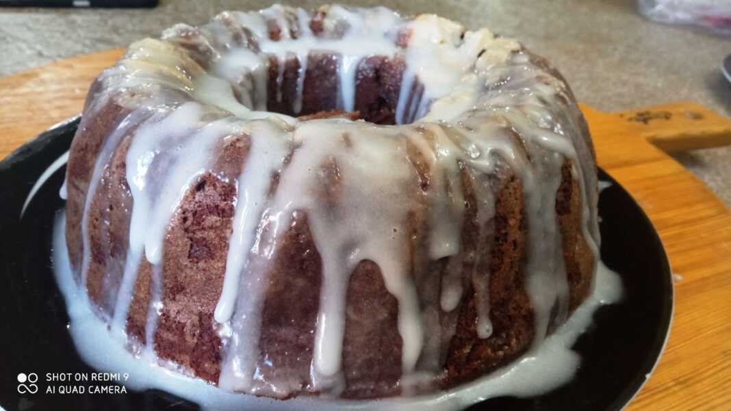 Ένα ψηλό και αφράτο κέικ φτιαγμένο από τριμμένα μελομακάρονα, καλυμμένο με λευκό γλάσο άχνης και πασπαλισμένο με καρύδια