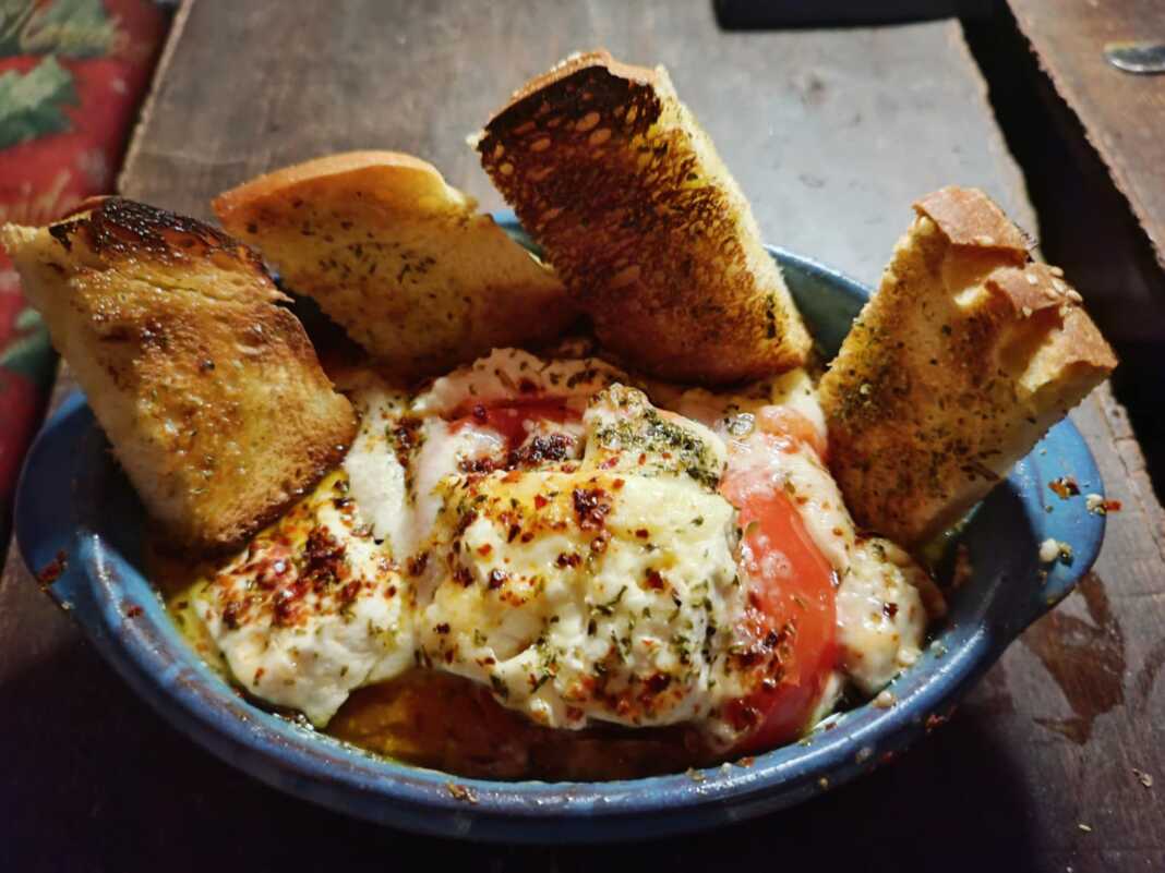 Πήλινο σκεύος με ζεστό, λιωμένο μπουγιουρντί με φέτα, ντομάτα και πιπεριές.