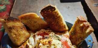 Πήλινο σκεύος με ζεστό, λιωμένο μπουγιουρντί με φέτα, ντομάτα και πιπεριές.