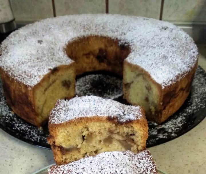 keik milou me kanela afrato Φωτογραφία με ένα κομμάτι κέικ μήλου πασπαλισμένο με άχνη ζάχαρη.