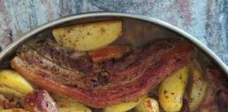 Χοιρινό φούρνου ζουμερό και καλοψημένο, σερβιρισμένο με πατάτες.