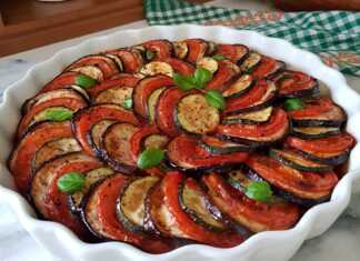 Πολύχρωμα στρώματα από φέτες μελιτζάνας, κολοκυθιού και ντομάτας τοποθετημένα κυκλικά σε ταψί πάνω σε κόκκινη σάλτσα