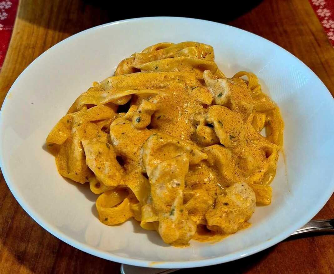 Πιάτο με ταλιατέλες, κοτόπουλο και κρεμώδη σάλτσα πέστο λιαστής ντομάτας, πασπαλισμένο με βασιλικό.