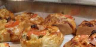 Ατομικές πίτσες σε ρολάκια με τυρί, αλλαντικά και λαχανικά, έτοιμες ψημένες σε ταψί.