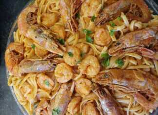 Πιάτο με λαχταριστή γαριδομακαρονάδα, με κόκκινη σάλτσα, λιγκουίνι, ψιλοκομμένο μαϊντανό και ολόκληρες γαρίδες από πάνω.