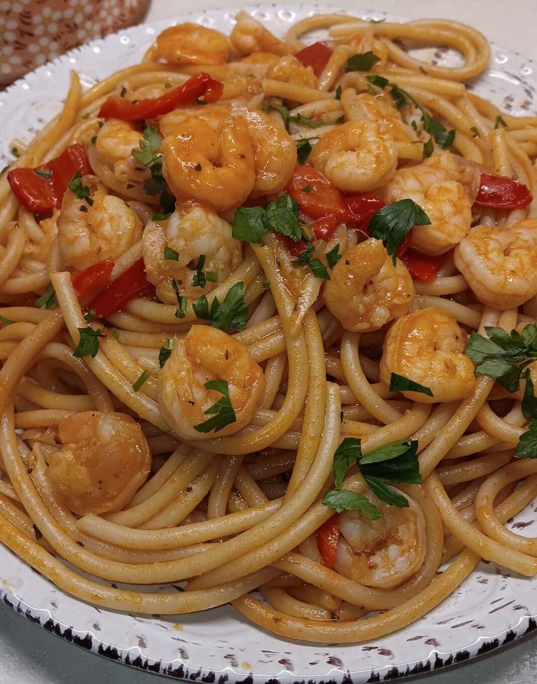 Ένα πιάτο με λαχταριστές γαρίδες ανακατεμένες με μακαρόνια και κόκκινη σάλτσα.