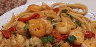 Ένα πιάτο με λαχταριστές γαρίδες ανακατεμένες με μακαρόνια και κόκκινη σάλτσα.