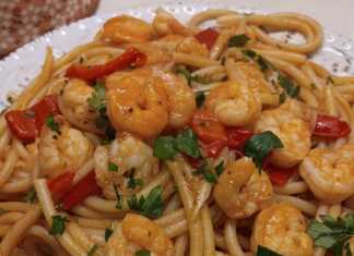 Ένα πιάτο με λαχταριστές γαρίδες ανακατεμένες με μακαρόνια και κόκκινη σάλτσα.