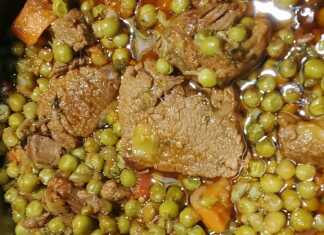 Μία κατσαρολα με μοσχαράκι κοκκινιστό, πράσινο αρακά και πορτοκαλί καρότα σερβιρισμένο σε βαθύ πιάτο.