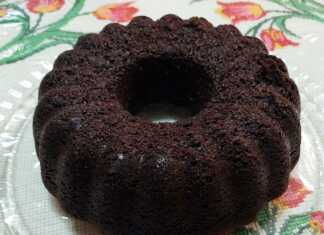 Ένα ψηλό και αφράτο νηστίσιμο σοκολατένιο κέικ, πασπαλισμένο με άχνη ζάχαρη, που δείχνει την αέρινη εσωτερική του δομή