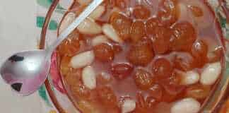 Γλυκό σταφύλι σε ένα μπολ, με τις ρώγες να γυαλίζουν στο σιρόπι και λίγα αμύγδαλα.