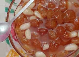 Γλυκό σταφύλι σε ένα μπολ, με τις ρώγες να γυαλίζουν στο σιρόπι και λίγα αμύγδαλα.