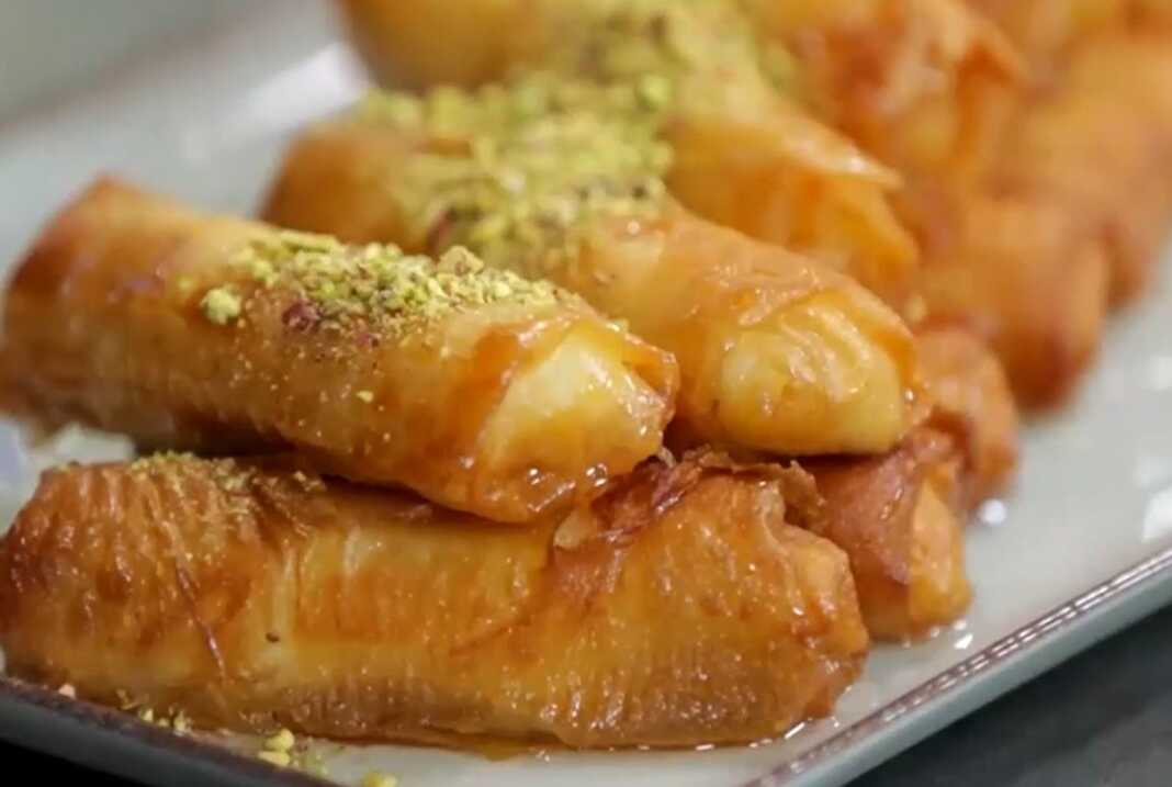 Τηγανητά γαλακτομπουρεκάκια χρυσαφένια και σιροπιασμένα σε ένα πιάτο.