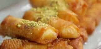 Τηγανητά γαλακτομπουρεκάκια χρυσαφένια και σιροπιασμένα σε ένα πιάτο.