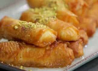 Τηγανητά γαλακτομπουρεκάκια χρυσαφένια και σιροπιασμένα σε ένα πιάτο.