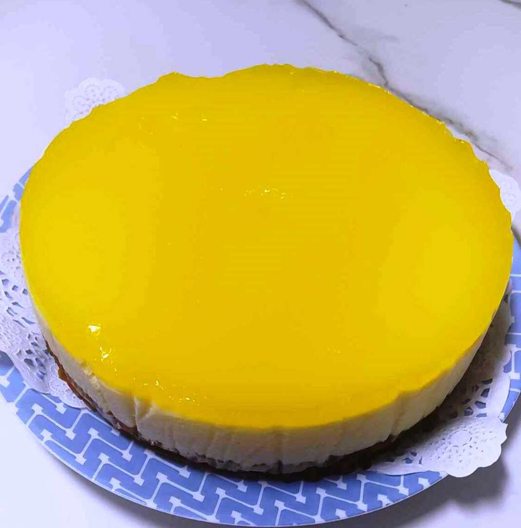 Φωτογραφία μιας λαχταριστής τούρτας λεμονιού με γυαλιστερή κίτρινη επικάλυψη.