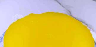 Φωτογραφία μιας λαχταριστής τούρτας λεμονιού με γυαλιστερή κίτρινη επικάλυψη.