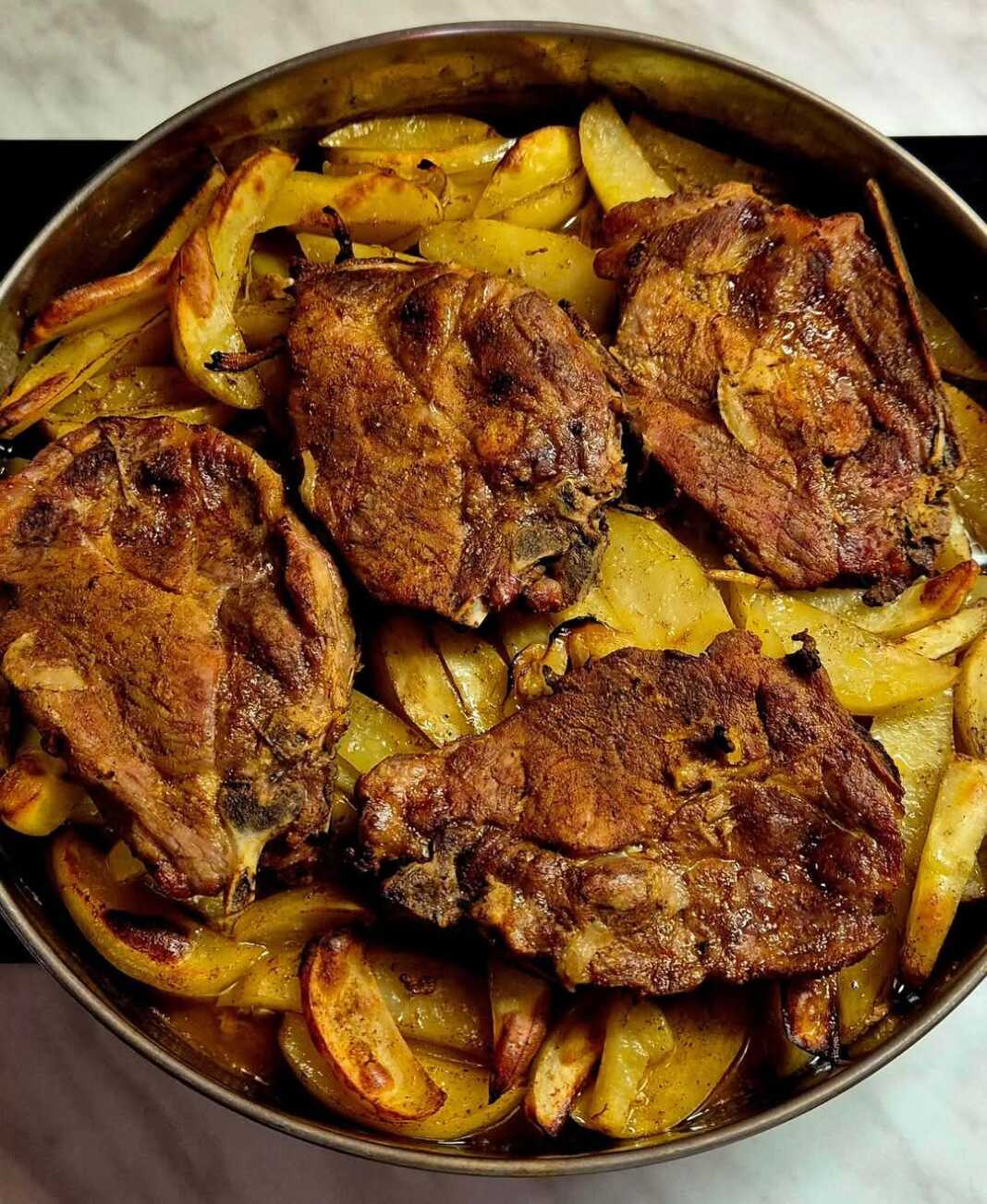 Λαχταριστές μπριζόλες λαιμού χοιρινές με κόκαλο ψημένες στο φούρνο μαζί με αρωματικές πατάτες. Ένα εύκολο και χορταστικό γεύμα.