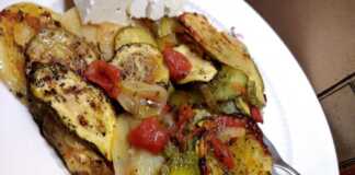 Ένα πιάτο με μπριάμ, γεμάτο πολύχρωμα καλοκαιρινά λαχανικά όπως μελιτζάνες, κολοκυθάκια, ντομάτες και πιπεριές