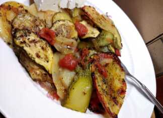 Ένα πιάτο με μπριάμ, γεμάτο πολύχρωμα καλοκαιρινά λαχανικά όπως μελιτζάνες, κολοκυθάκια, ντομάτες και πιπεριές