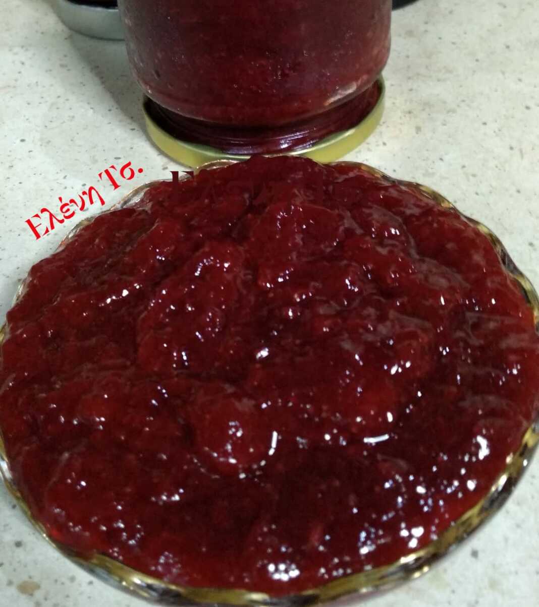 Βάζο με σπιτική κόκκινη μαρμελάδα φράουλα, με ορατά κομμάτια φρούτων, δίπλα σε φρέσκες φράουλες.