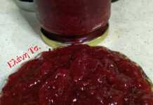 Βάζο με σπιτική κόκκινη μαρμελάδα φράουλα, με ορατά κομμάτια φρούτων, δίπλα σε φρέσκες φράουλες.