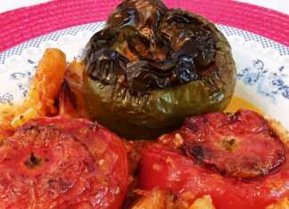 Ένα ταψί με γεμιστές ντομάτες, πιπεριές και μελιτζάνες, ανάμεσα σε κομμένες πατάτες.