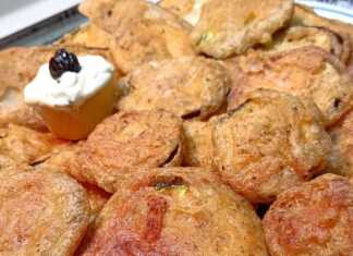 Ένα πιάτο με χρυσαφένια, τραγανά τηγανητά κολοκυθάκια και ένα μπολάκι με λευκή σως γιαουρτιού.