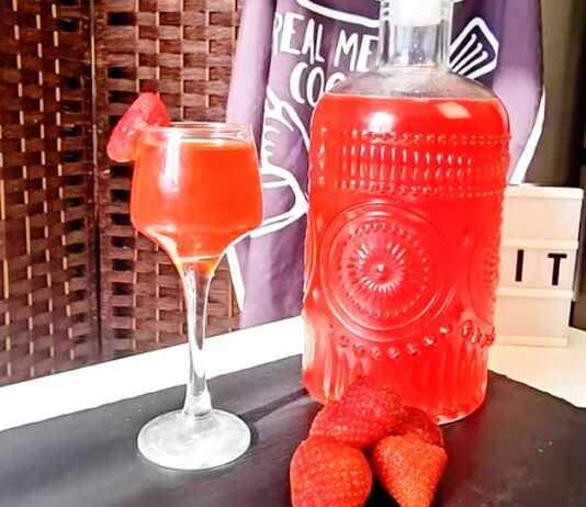 Ένα μπουκάλι γεμάτο με κόκκινο σπιτικό λικέρ φράουλας.