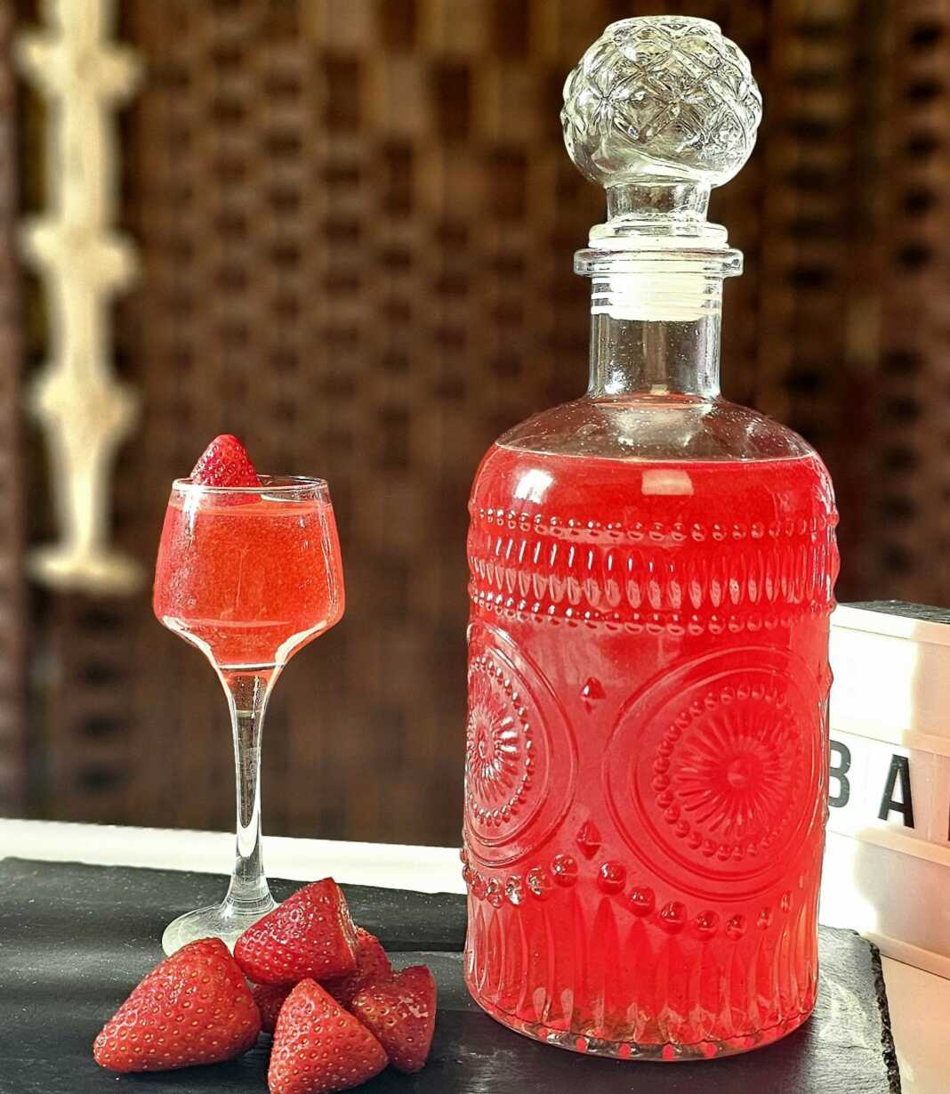 Ένα μπουκάλι γεμάτο με κόκκινο σπιτικό λικέρ φράουλας.