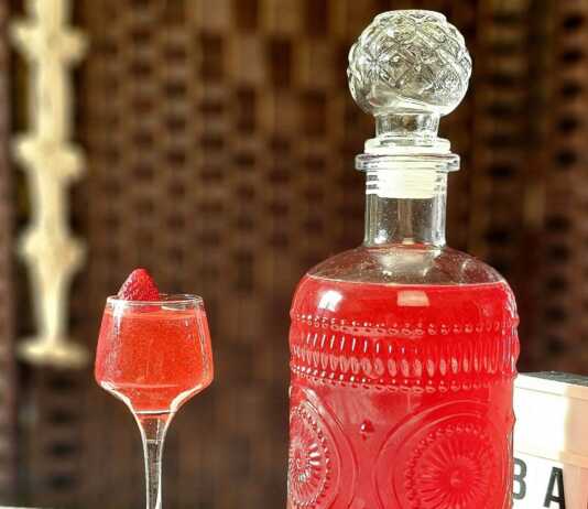 Ένα μπουκάλι γεμάτο με κόκκινο σπιτικό λικέρ φράουλας.