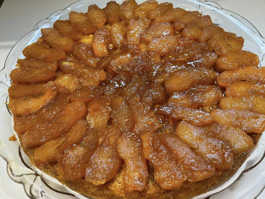 Μηλόπιτα αναποδογυρισμένη σε πιατέλα, με την γυαλιστερή καραμέλα πορτοκαλιού και τα μήλα στην κορυφή.