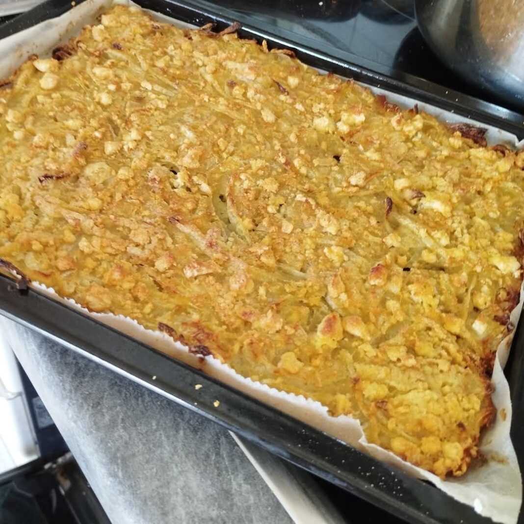 Ένα ταψί με ψημένη κρεμμυδόπιτα, με χρυσαφένια επιφάνεια.