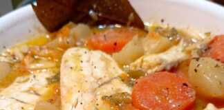 Ψαρόσουπα με λαβράκι Πιάτο με ζεστή ψαρόσουπα λαβράκι, γεμάτη λαχανικά και κομμάτια ψαριού, γαρνιρισμένη με φρέσκα μυρωδικά σε ξύλινο τραπέζι.