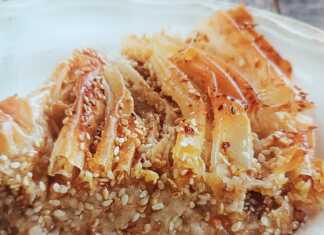 Σιροπιαστή σουσαμόπιτα σε πλισέ σχήμα, κομμένη σε μερίδες και περιχυμένη με χρυσαφένιο σιρόπι.