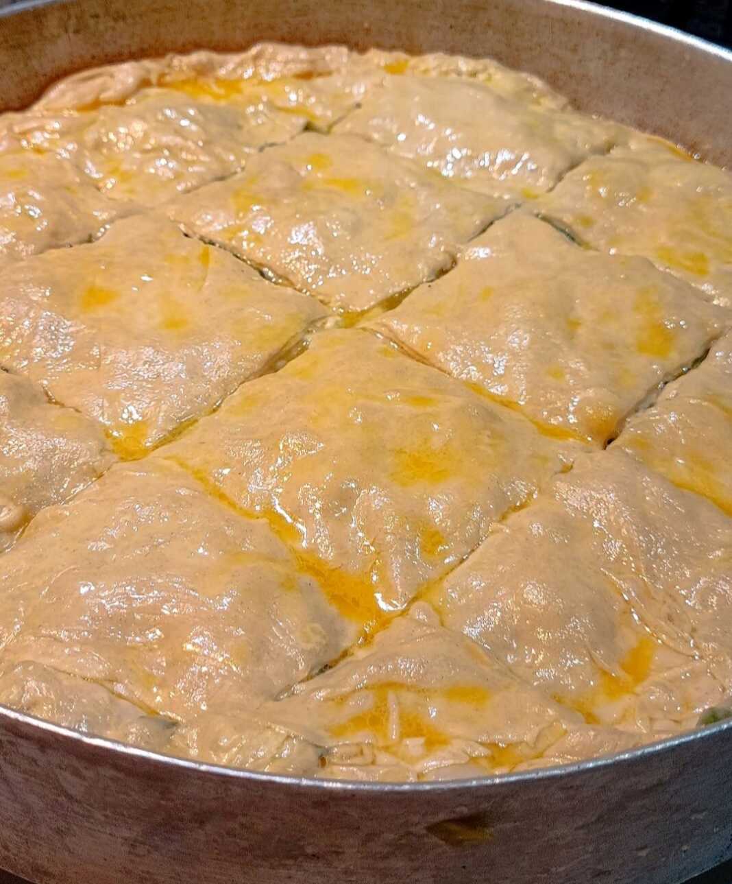 spanako_xeiropoitio filo Δύο σπανακόπιτες, μία στρογγυλή μεγάλη και μερικές μικρότερες στριφτές, με χρυσαφένιο χειροποίητο φύλλο.