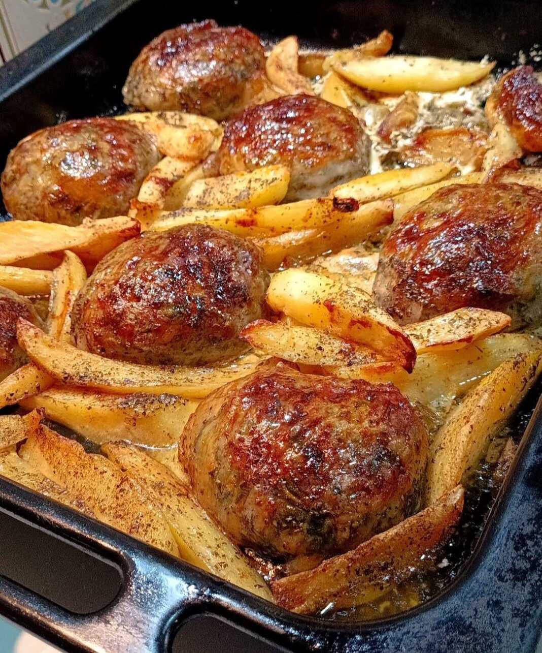 Ένα ταψί με χρυσαφένια τσιγέρια, μικρά τυλιχτά από αρνίσια μπόλια, ανάμεσα σε προτηγανισμένες πατάτες.