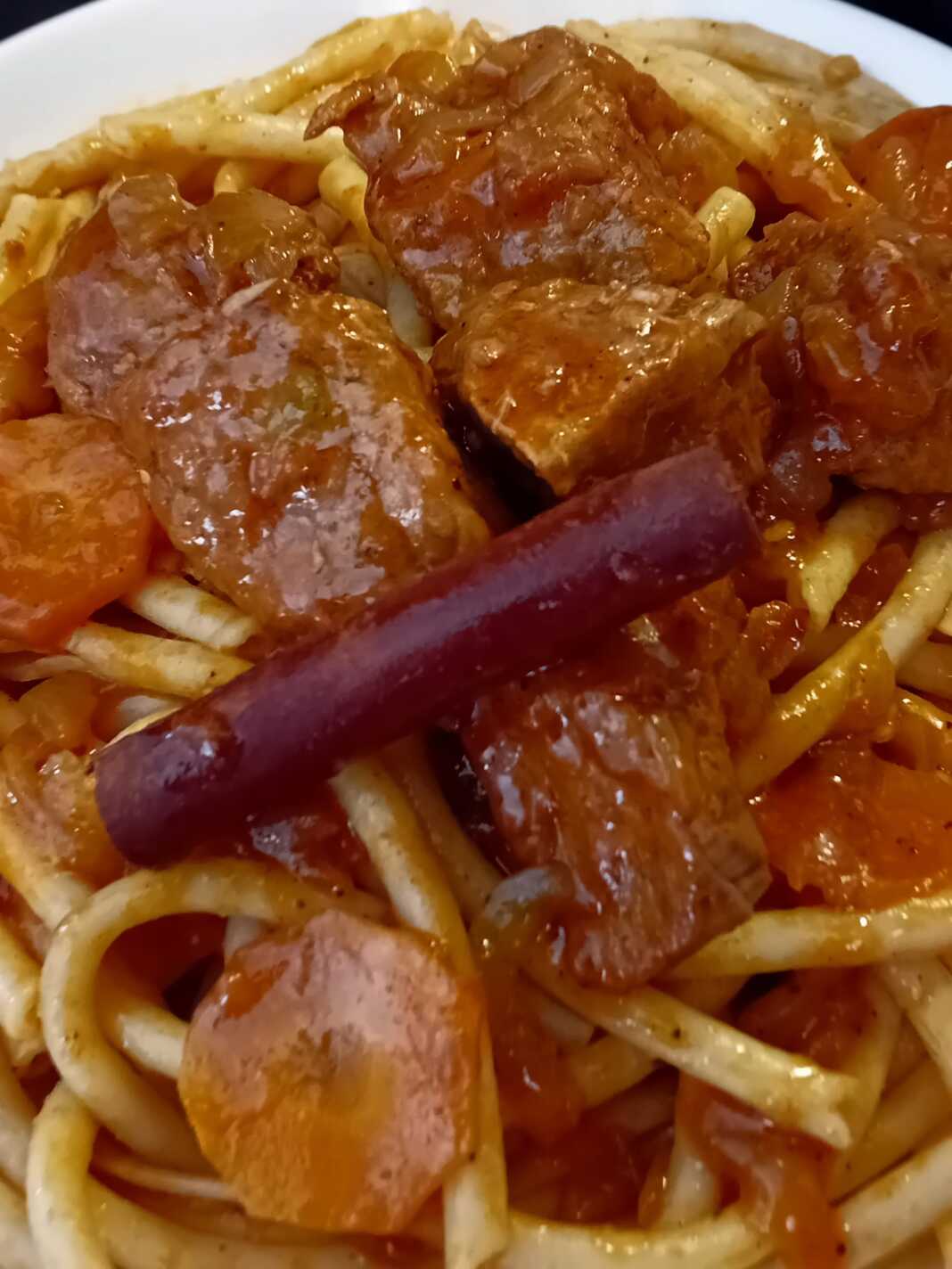 Πιάτο με Κερκυραϊκή Παστιτσάδα, με μακαρόνια και κομμάτια μοσχαριού σε πλούσια κόκκινη σάλτσα.