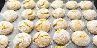 Μαλακά μπισκότα λεμονιού πασπαλισμένα με άχνη ζάχαρη σε ένα ταψί.