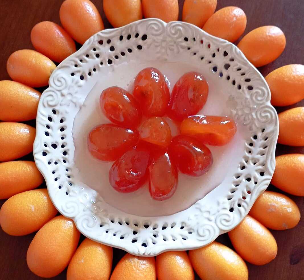 Γυάλινο βάζο με λαμπερά, ολόκληρα κουμ κουάτ γλυκό του κουταλιού, μέσα σε διαυγές σιρόπι.